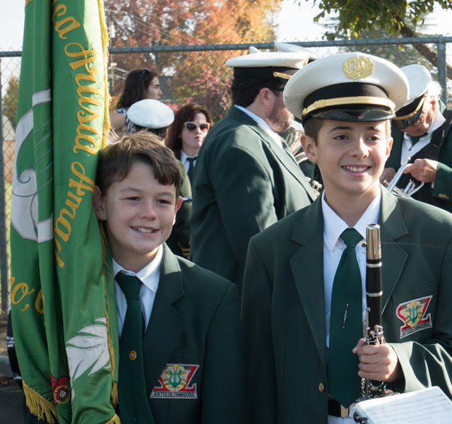 Two young members posed and smiling, holding a clarinet and a flag